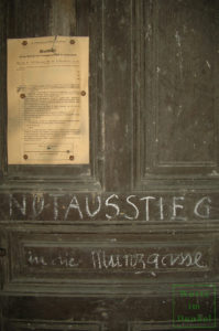 Luftschutzmerkblatt und Kreidebeschriftung an einer Kellertür