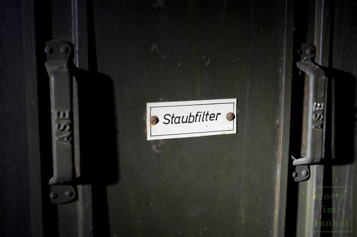 Plakette "Staubfilter", auf den Handgriffen, die dem Ein- und Ausziehen der Filter dienen, steht der Begriff "ASE", möglicherweise der Hersteller der Staubfilter