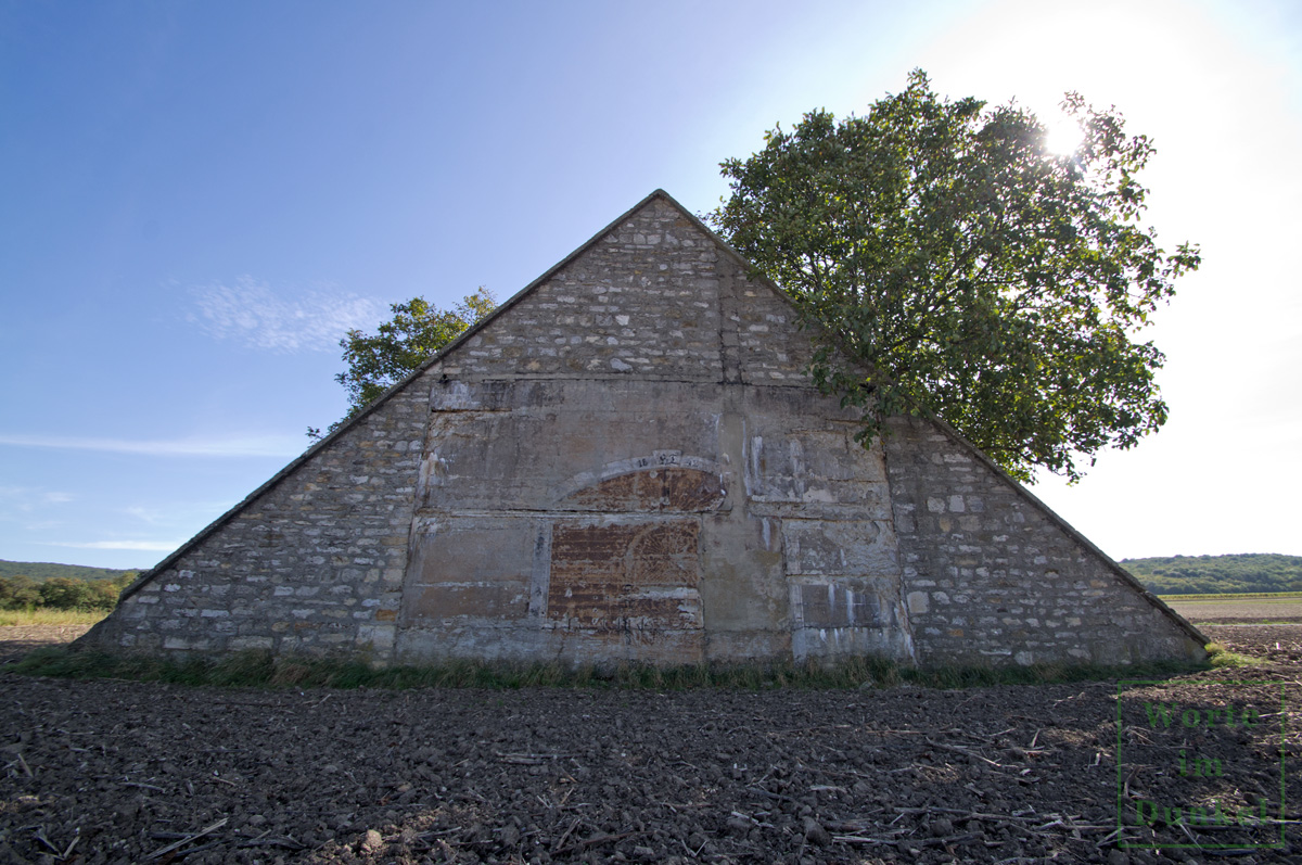 Dieser Bunker wurde mit einer dreieckigen Scheinfassade ausgestattet und diese sogar mit einem aufgemalten Tor und der Jahreszahl HT 1942 versehen.