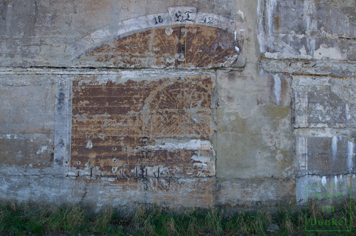 Dieser Bunker wurde mit einer dreieckigen Scheinfassade ausgestattet und diese sogar mit einem aufgemalten Tor und der Jahreszahl HT 1942 versehen – Detail.